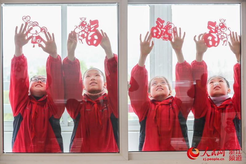 2020年1月7日，浙江湖州市德清縣乾元鎮中心小學學生將生肖豬“鼠”、福字等剪紙作品貼在教室的玻璃上。王正攝