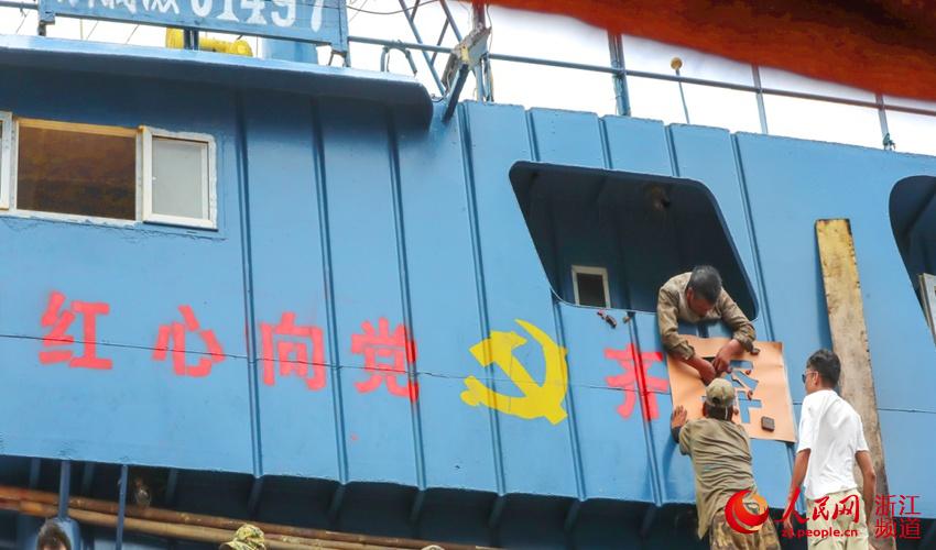渔民在船身上刷上党徽和“红心向党 齐奔小康”字样。