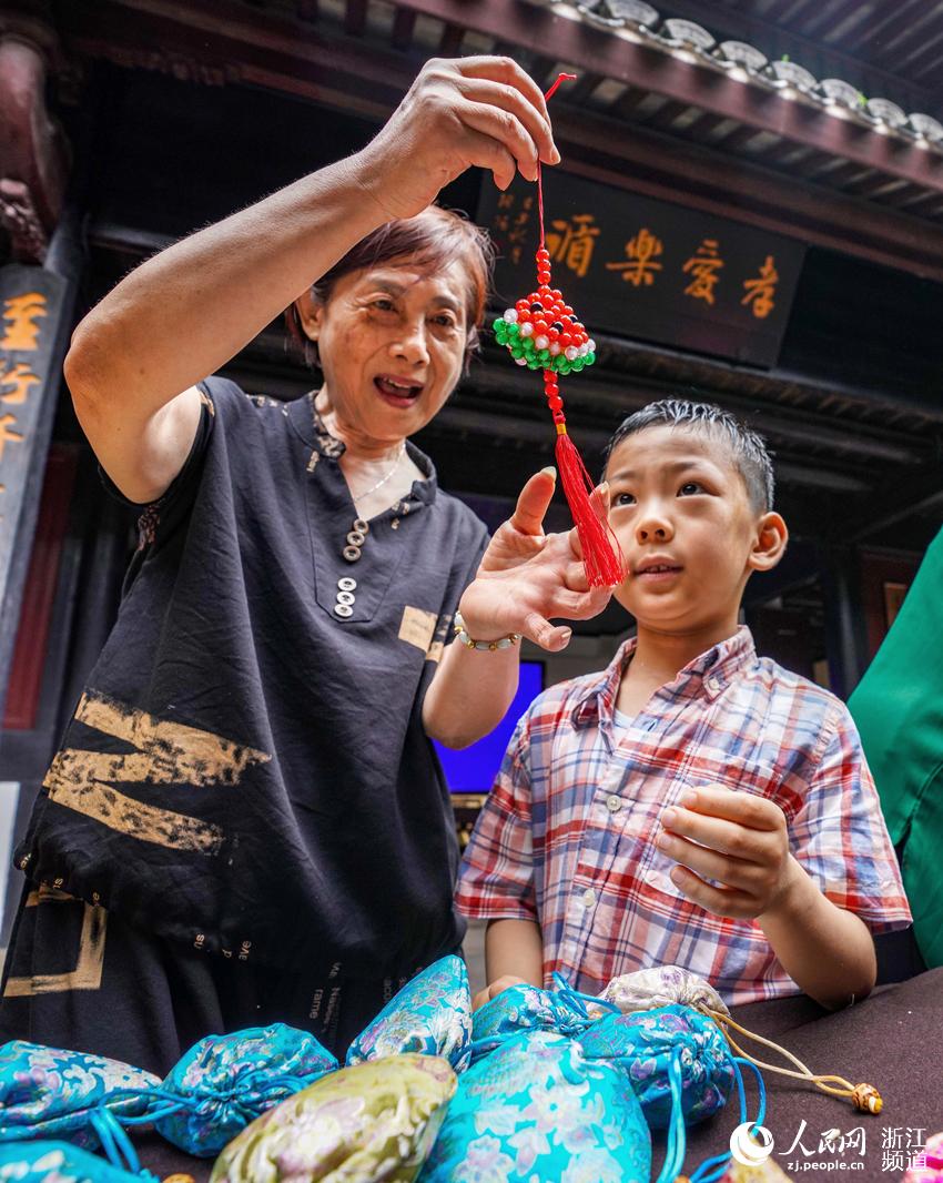 6月10日，在宁波市江北区慈城镇慈孝馆，社区阿姨与幼儿园小朋友们共同包粽子、做香袋，让小朋友们感受中华传统文化的魅力。人民网 章勇涛摄