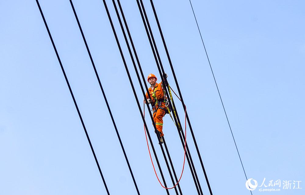 3月11日，在浙江省諸暨市河上鎮，浙江省送變電工程有限公司檢修人員在高空的導線上進行線路檢修維護。人民網 章勇濤攝