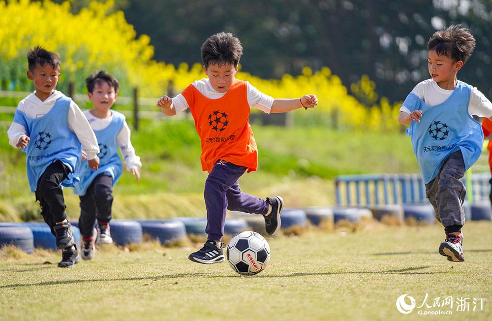 3月16日，在浙江省慈溪市周巷镇天元实验幼儿园，小朋友们在绿茵场上进行足球比赛。人民网 章勇涛摄