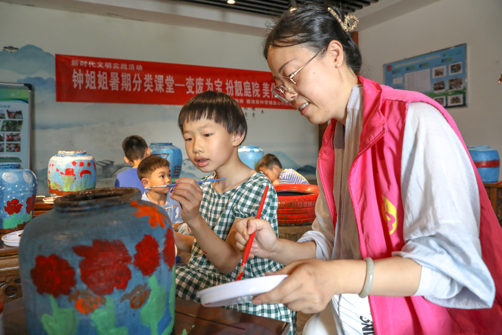 “钟姐姐”志愿者带着小朋友对废弃瓦罐进行艺术创造。白羽摄