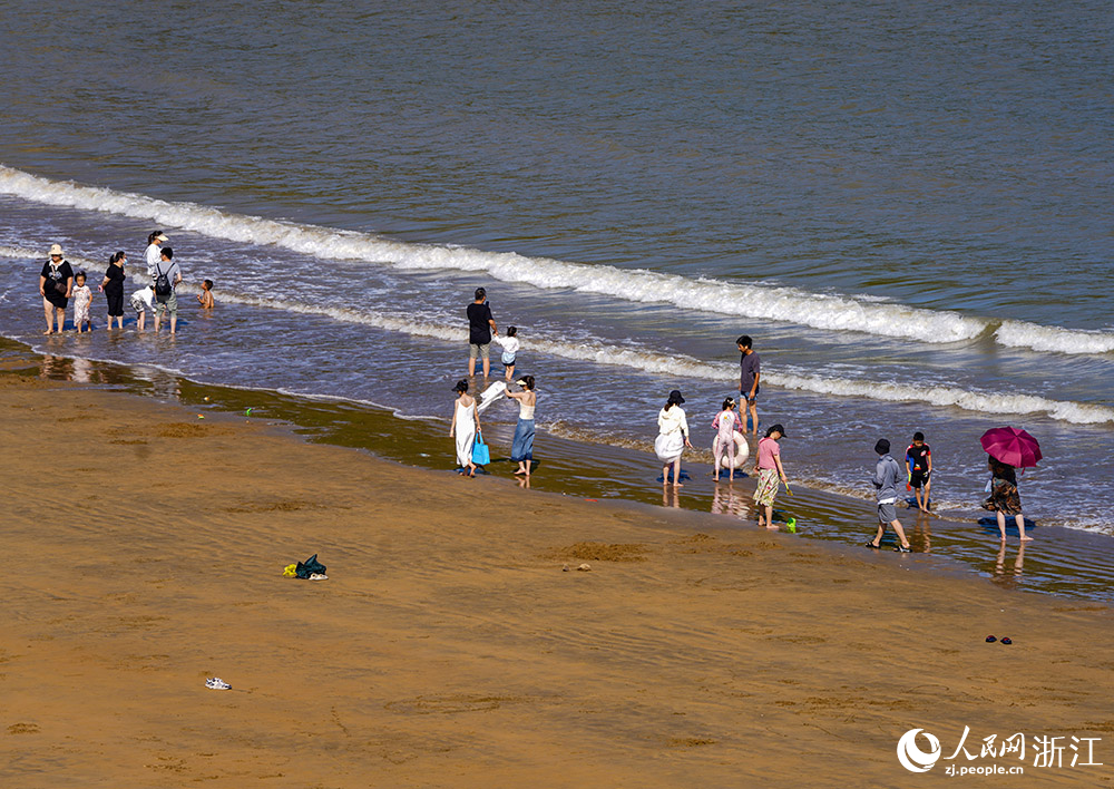 在舟山市岱山县秀山岛，游客尽情地踏浪戏水，欣赏美景。人民网 章勇涛摄