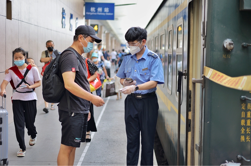 杭州站始发的K529次列车车门口，正迎接旅客上车的列车员张洋斌，在始发时需要站岗半个多小时，他时而弯腰帮助旅客提行李，时而认真核验车票，时而帮助重点旅客上车。周围摄