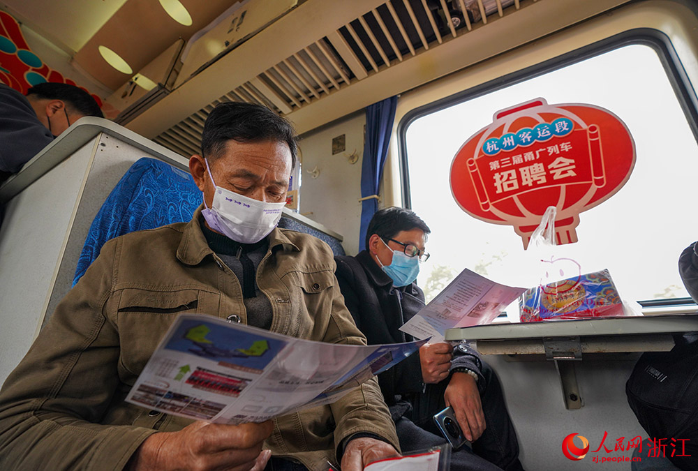 2月6日，在K210次列车上，乘客在阅读招工简介。人民网 章勇涛摄