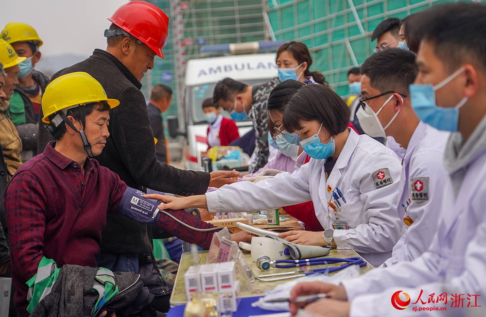 3月1日，在杭州市拱墅区石桥街道，一名医护志愿者在为工人测量血压。人民网 章勇涛摄