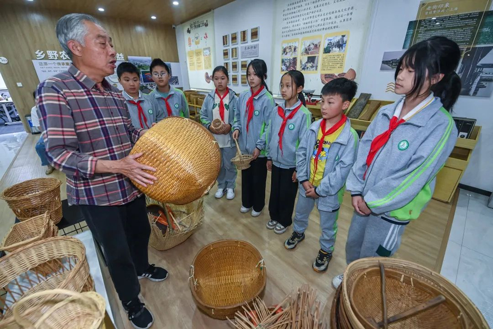柳编艺人给学生讲述柳编制品的工艺和历史。徐昱摄