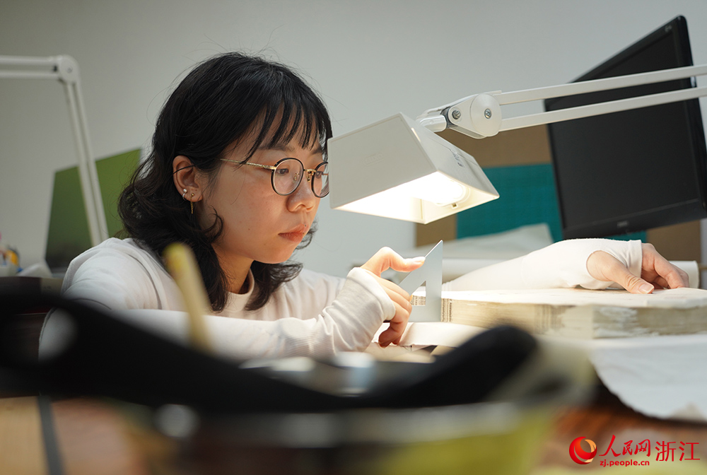 古籍修复师将修复好的古籍进行装订前的检查。人民网 章勇涛摄