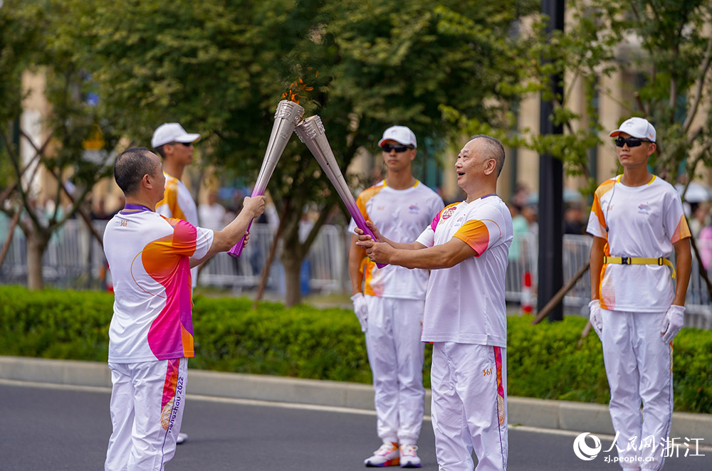 9月14日，第168棒火炬手李值（右）與第169棒火炬手洪軍武在點位交接。人民網 章勇濤攝