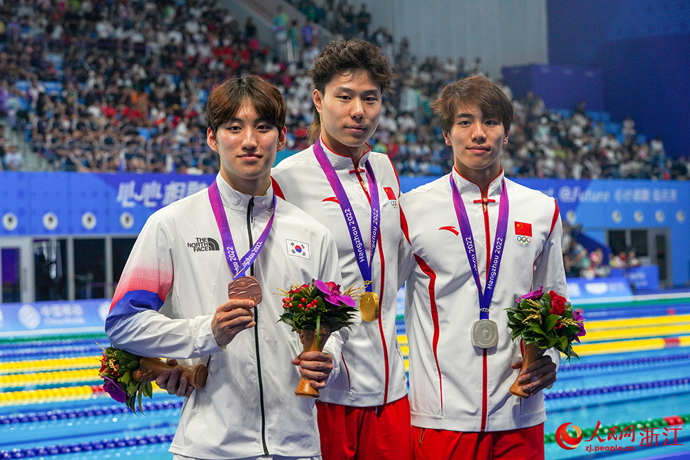 9月29日，杭州亞運會游泳比賽在杭州奧體中心游泳館迎來收官日。中國隊選手覃海洋（中）在男子50米蛙泳決賽中奪得冠軍。人民網 章勇濤攝