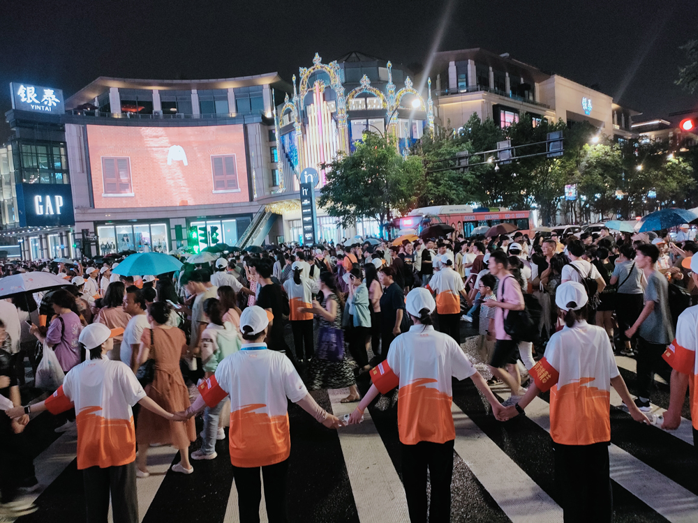 志愿者手拉手筑成一道人墙，帮助交警管控人流。湖滨街道供图