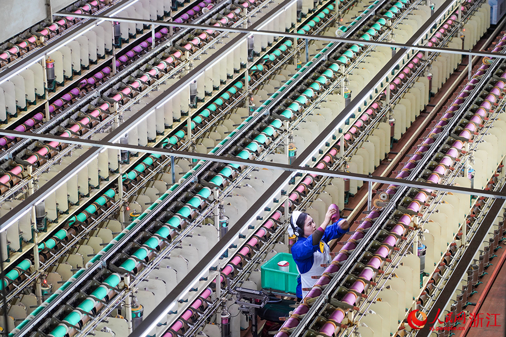 浙江省紹興市新昌縣達利絲綢智能工廠內一派繁忙，工人在生產線上趕制訂單。人民網 章勇濤攝