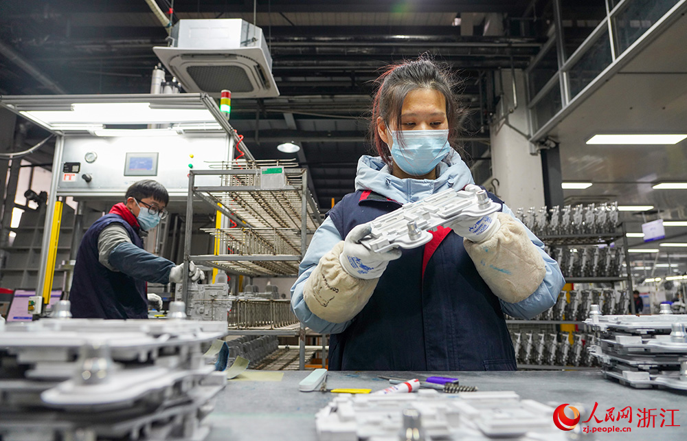 近日，在浙江省台州市天台县一汽车零部件企业车间，工人在智能化设备的协助下赶制订单。人民网 章勇涛摄