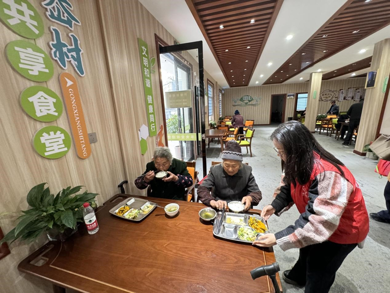 “香溢”志愿者在共享食堂为老人们端上饭菜。张旦颖摄
