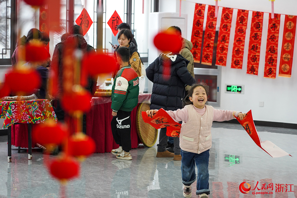 2月3日，在浙江省余姚市鹿亭鄉，小朋友手持春聯歡樂地奔向家人。人民網 章勇濤攝