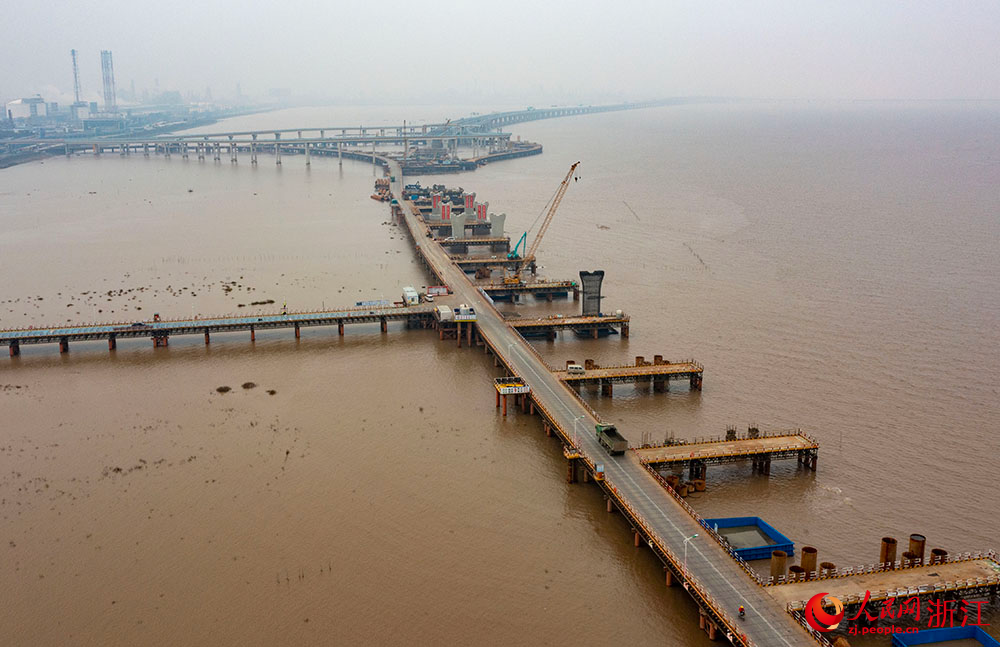3月12日，在寧波市鎮海區灰鱉洋南岸灘涂之上，工人在棧橋搭建起的海上施工通道上有序施工。人民網 章勇濤攝