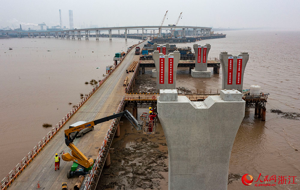 3月12日，在宁波市镇海区灰鳖洋南岸滩涂之上，工人在栈桥搭建起的海上施工通道上有序施工。人民网 章勇涛摄