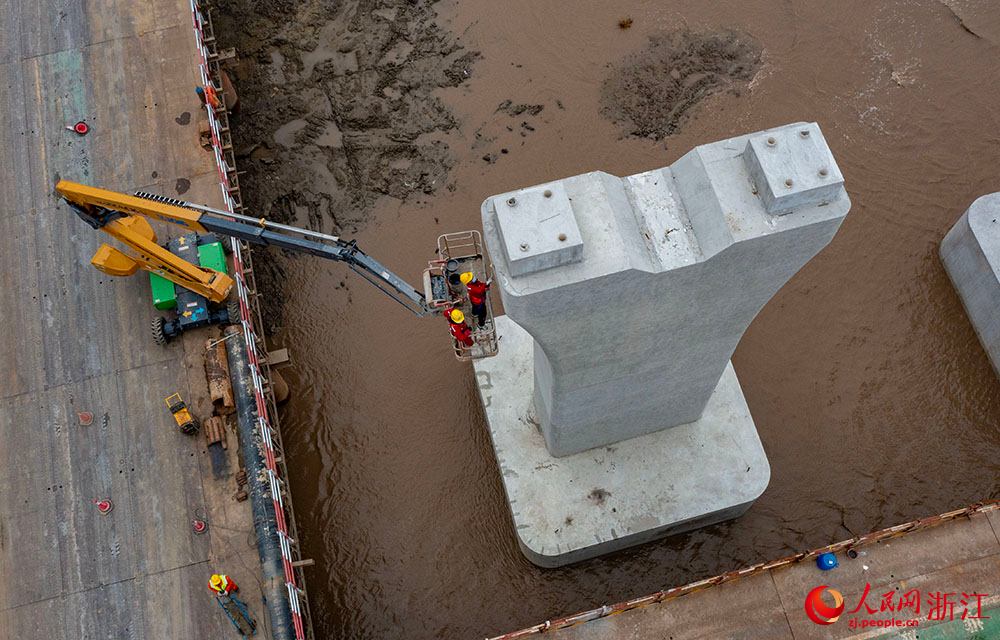 3月12日，在宁波市镇海区灰鳖洋南岸滩涂之上，工人在栈桥搭建起的海上施工通道上有序施工。人民网 章勇涛摄