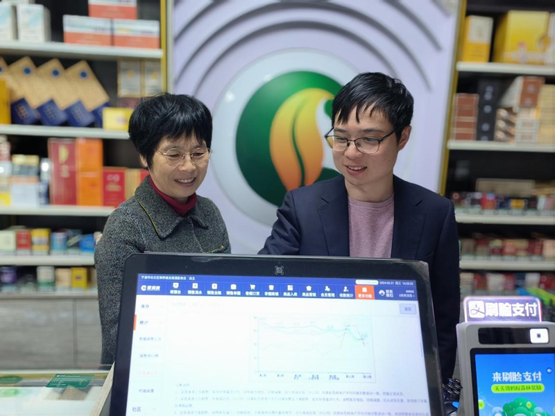 “香溢”志愿者（右）向零售户展示双屏机新功能。龚丽娜摄