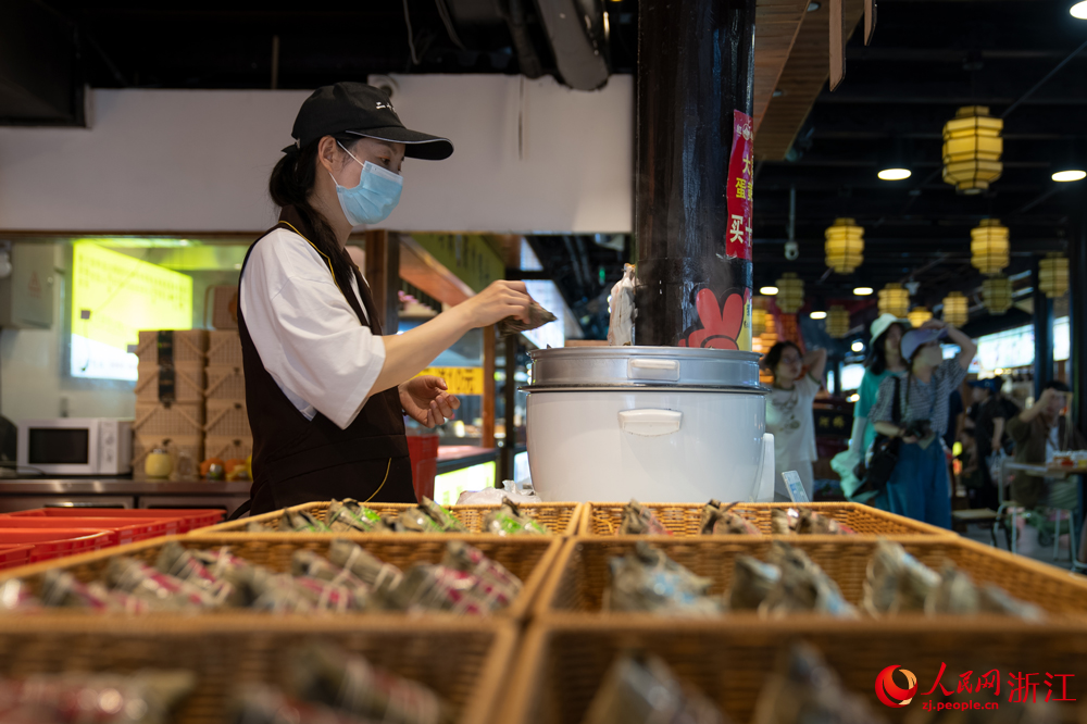 5月26日，端午将至，浙江省嘉兴市月河街的一处店铺内，店员将刚包好的粽子放入锅中。人民网记者 葛泰佚摄