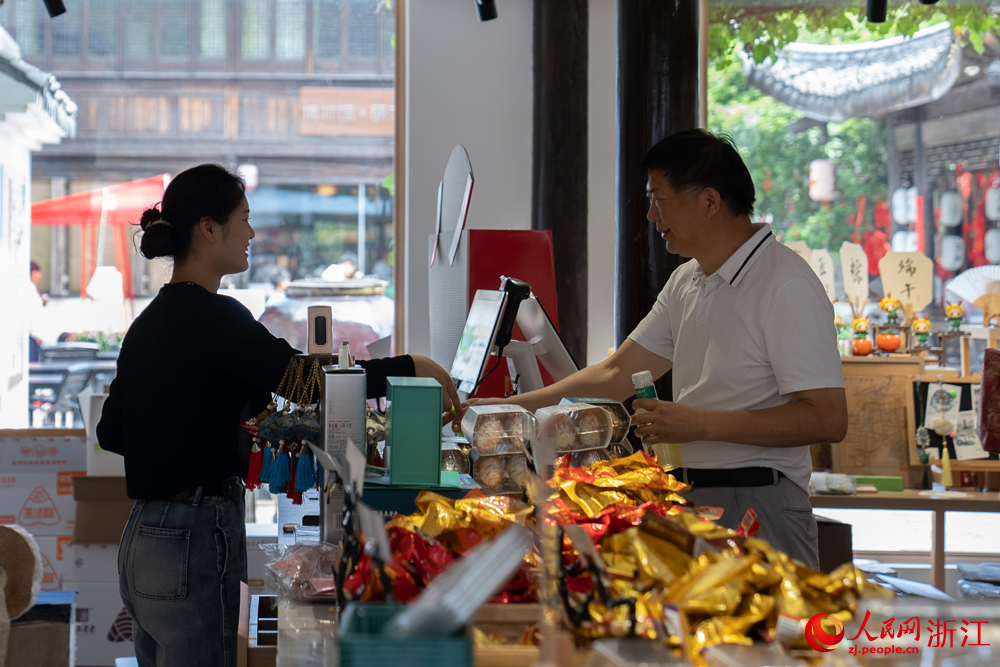 5月26日，浙江省嘉兴市月河街上的一处店铺内，游客在咨询粽子价格。人民网记者 葛泰佚摄