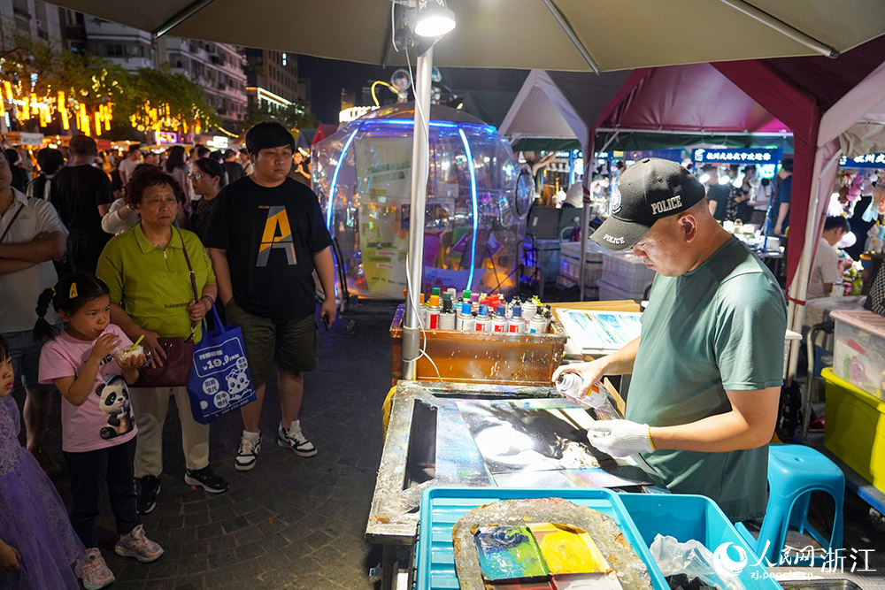 5月24日，杭州武林夜市里的油漆画吸引游客围观。人民网  章勇涛摄