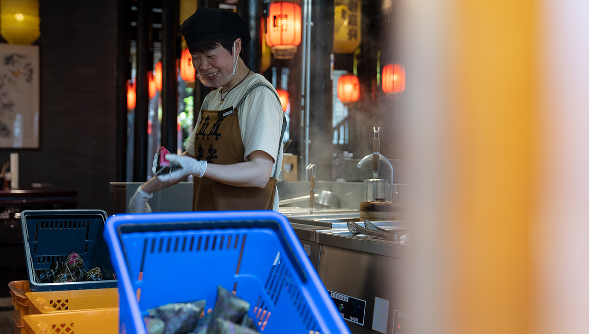 5月26日，浙江省嘉興市月河街的一處店鋪內，一名店員在熱氣騰騰的鍋爐旁整理粽繩。人民網記者 葛泰佚攝