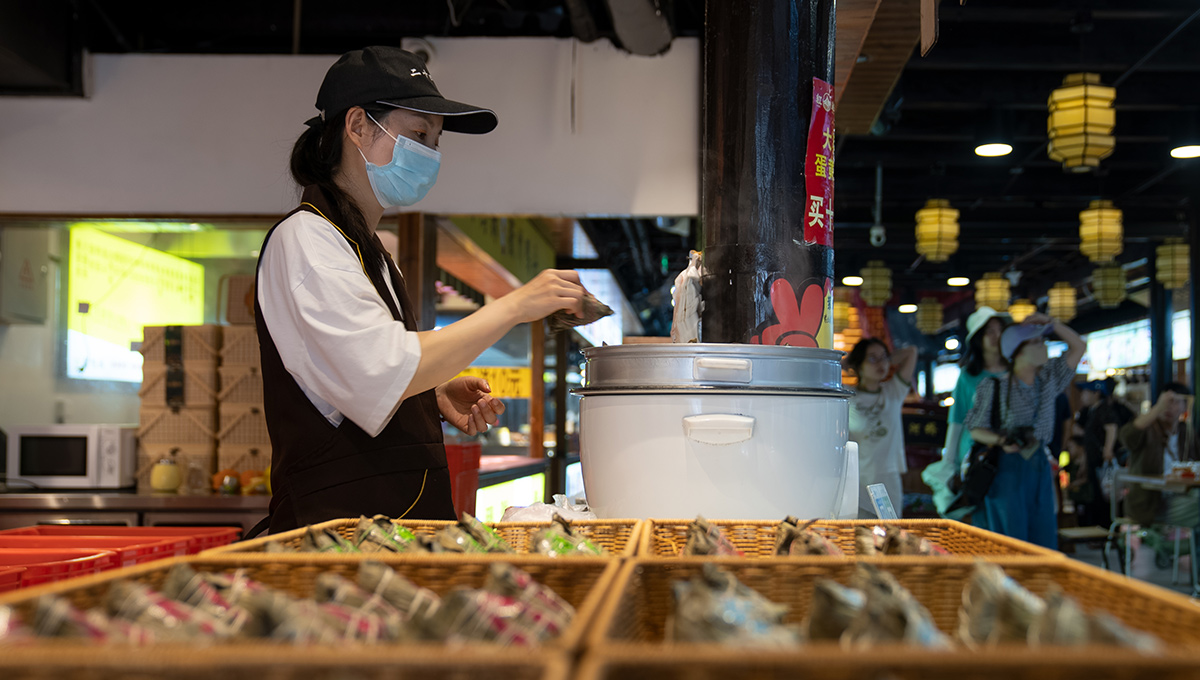 5月26日，端午將至，浙江省嘉興市月河街的一處店鋪內，店員將剛包好的粽子放入鍋中。人民網記者 葛泰佚攝