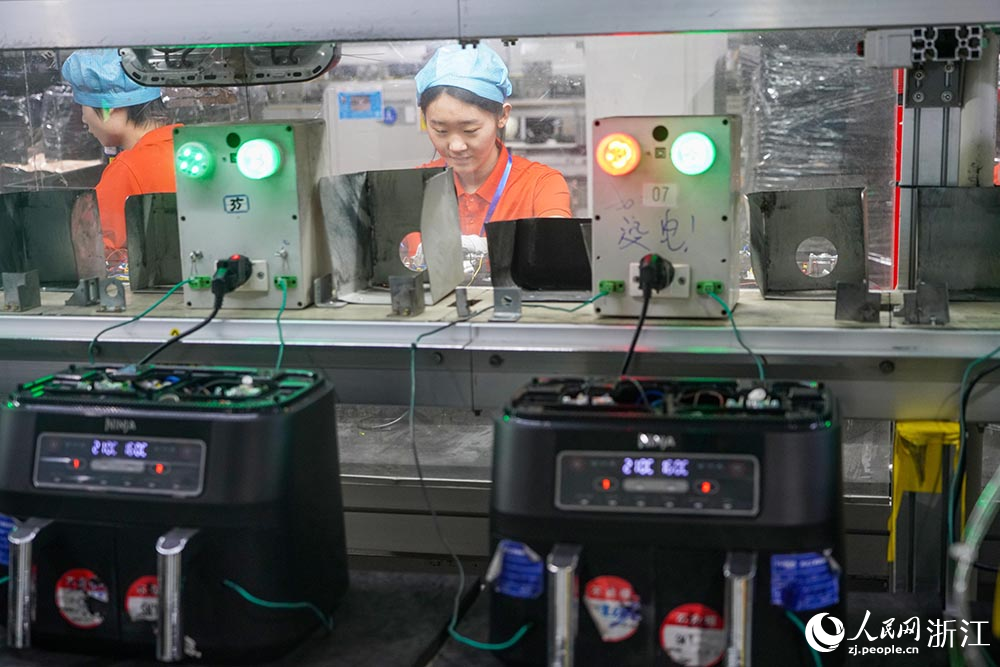 在浙江省慈溪市观海卫镇一家制造空气炸锅的企业，工人在生产线上忙碌着。人民网 章勇涛摄