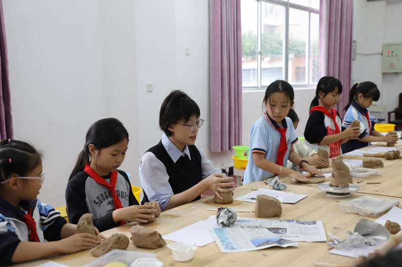 非遗老师叶芳正耐心地指导学生捏塑技巧，她还时不时地插入龙泉青瓷文化知识讲解