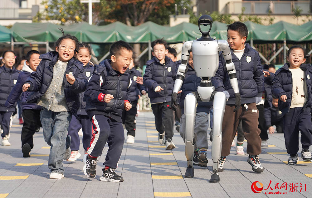 在寧波市江北區慈城懷之幼兒園，孩子們和人形機器人奔跑在校園裡。人民網 章勇濤攝