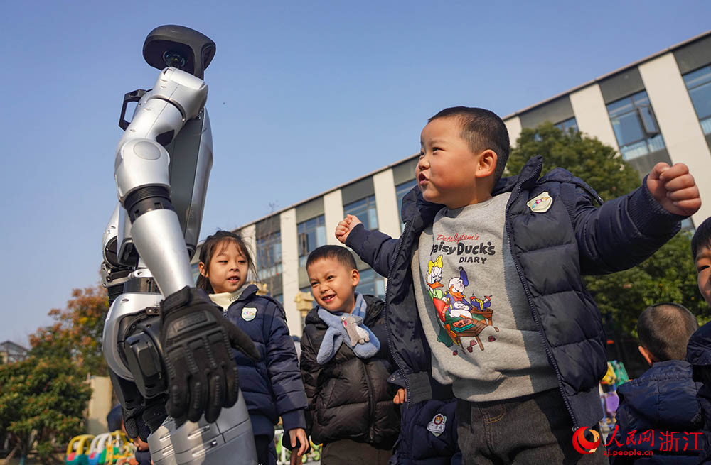 在宁波市江北区慈城怀之幼儿园，小朋友和人形机器人互动。人民网 章勇涛摄