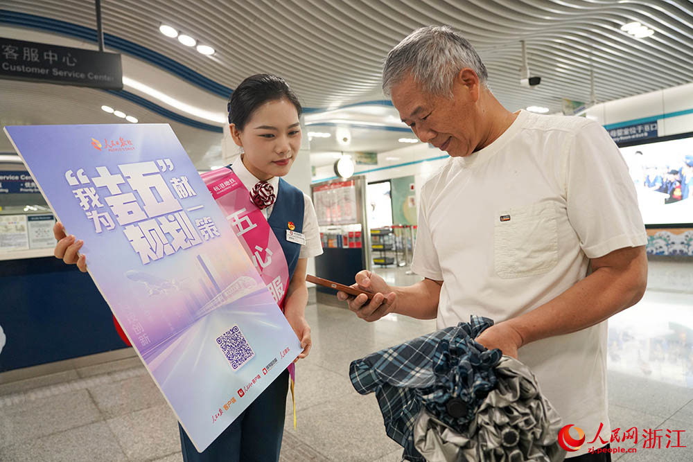 6月11日，在杭州地铁5号线，杭港地铁“五心服务队”队员引导乘客参与“我为‘十五五’规划献一策”活动。人民网 章勇涛摄