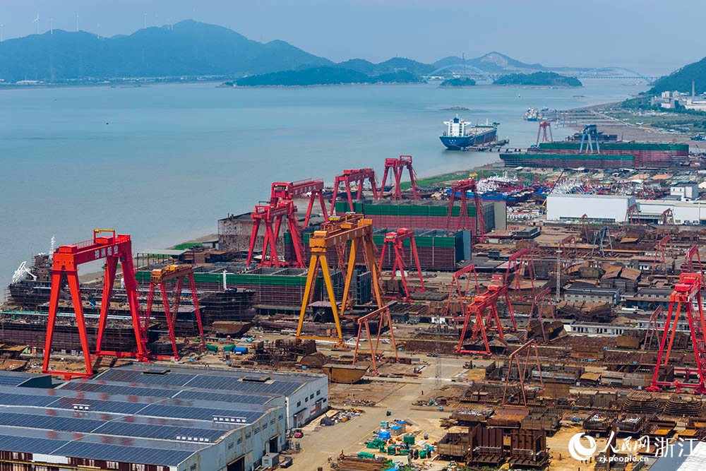 在浙江省寧波市象山縣石浦鎮打鼓峙臨港裝備制造基地，巨大的龍門吊緩緩移動，吊臂車在船體間穿梭自如，呈現一派熱火朝天的生產景象。人民網 章勇濤攝