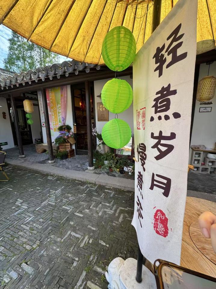 院内的油纸伞下，“轻煮岁月慢煮茶”七个字好似节拍器一般放慢了来客的步伐。人民网记者 龚莎摄