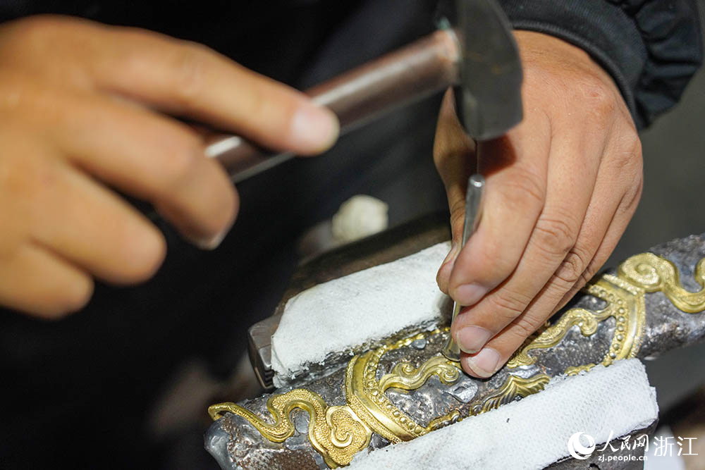 在浙江省龙泉市沈广隆剑铺，铸剑师对龙泉宝剑的剑鞘进行铜饰加工。人民网 章勇涛摄