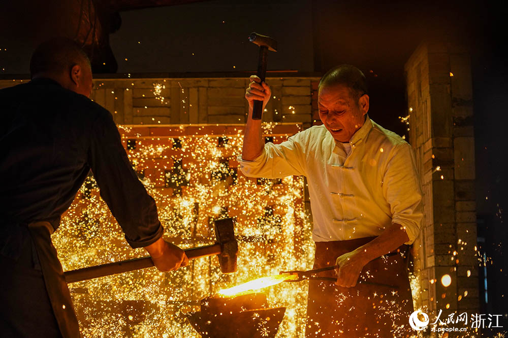 在浙江省龙泉市沈广隆剑铺，沈新培（右）正在锻打宝剑剑坯。人民网 章勇涛摄