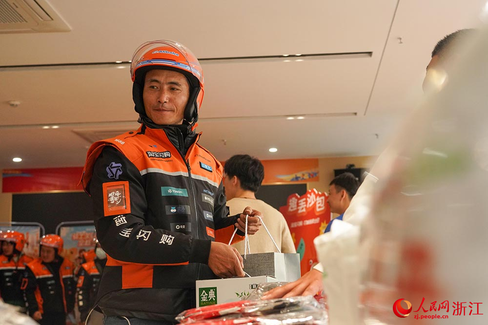 在宁波市江北区一处新就业群体服务点，外卖员领取暖冬物品。人民网  章勇涛摄