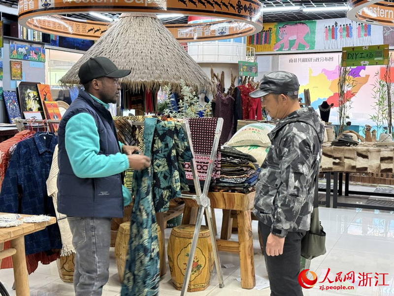 丹尼尔（左）正在给客人介绍商品。人民网记者 方彭依梦摄