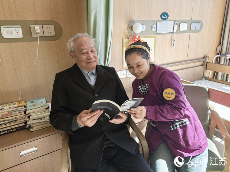 李平(左)在护理员陪伴下看书。人民网记者 王继亮摄