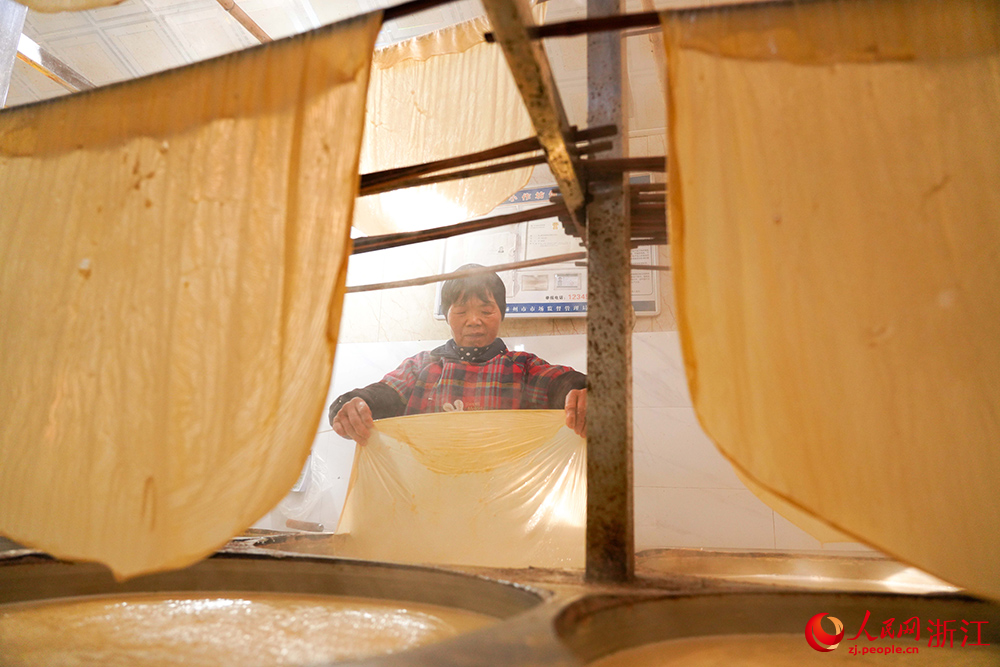 嵊州市崇仁镇的一豆腐皮作坊内雾气缭绕、豆香四溢，村民正忙着制作豆腐皮。人民网 章勇涛摄