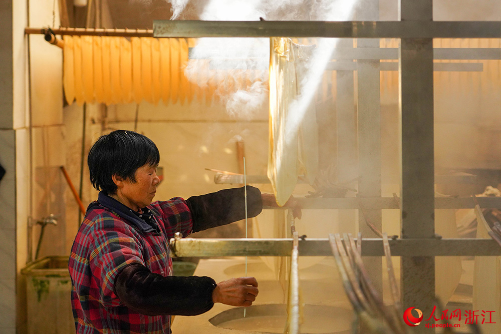 嵊州市崇仁鎮的一豆腐皮作坊內霧氣繚繞、豆香四溢，村民正忙著制作豆腐皮。人民網 章勇濤攝