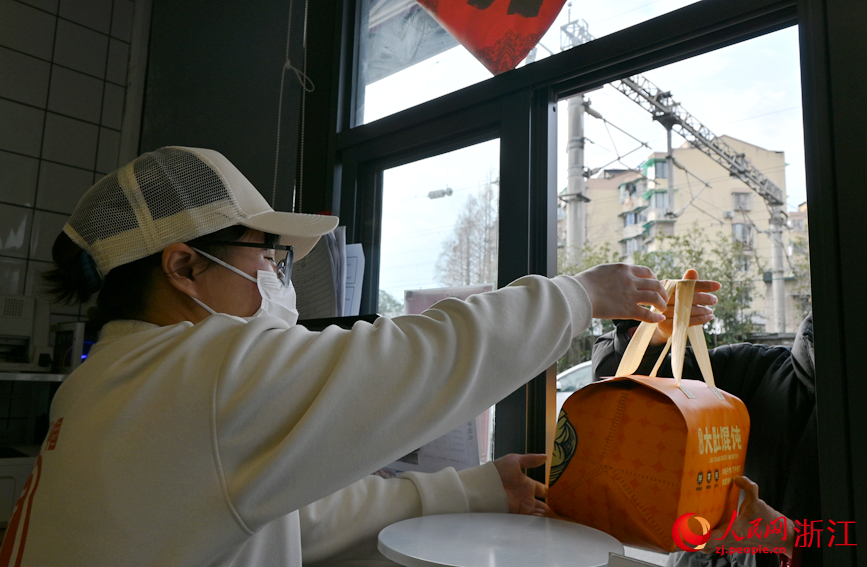 毛夏超将打包好的馄饨递给客户。人民网记者 张丽玮摄