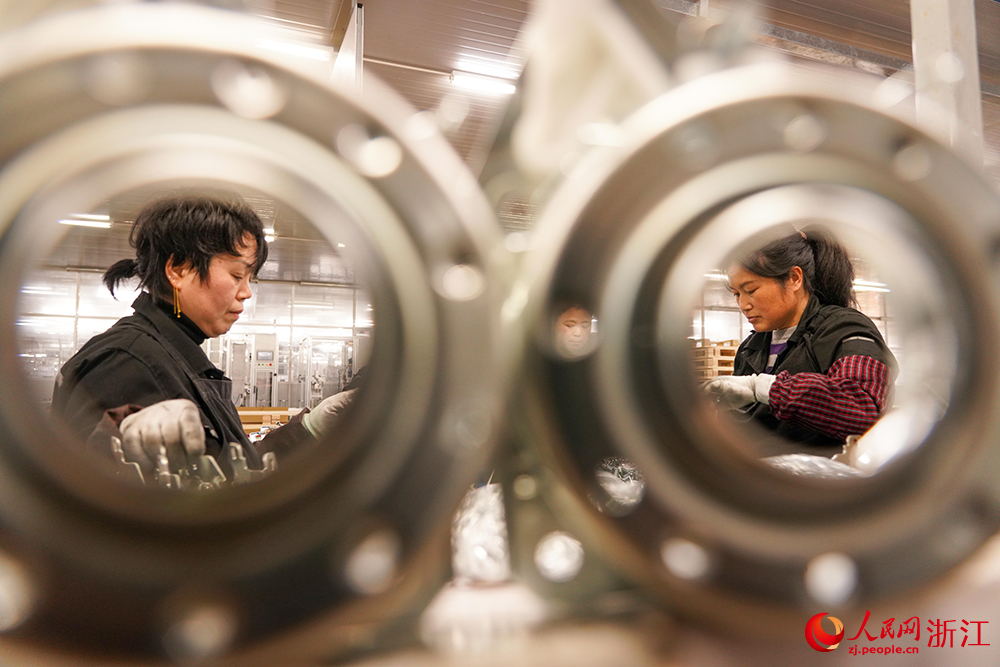 在寧波市寧海縣一家企業，離合器裝配線上兩位工人在進行殼體組件組裝。人民網 章勇濤攝
