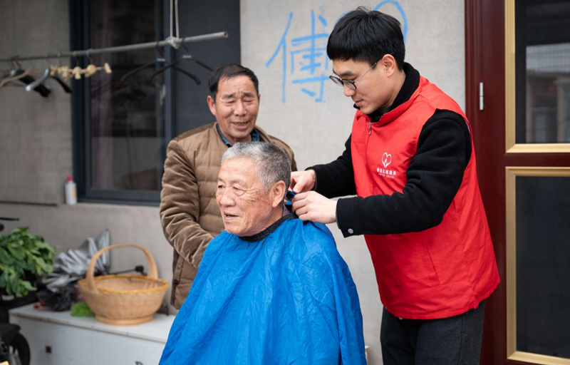 志愿者跟随樊仁生为村中老人理发。郑乙涛摄