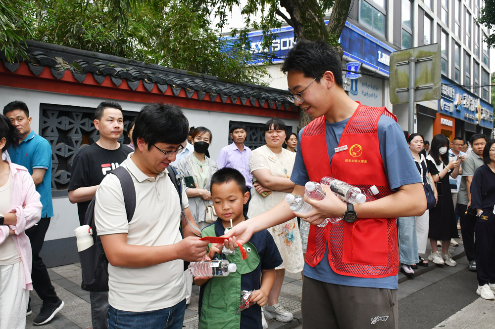 在考点外的家长等候区，镇海中学社团成员为驻足等候的家长递水送凉。罗梦圆摄