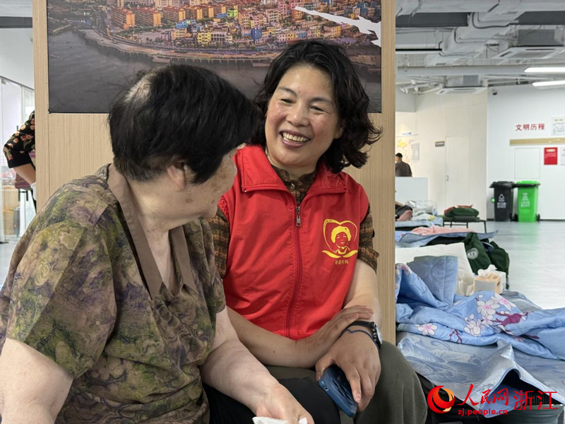 在避灾安置点，王银玉陪老人聊天。人民网记者 方彭依梦摄