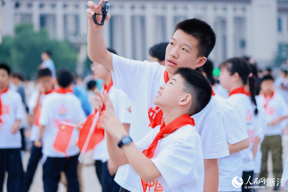 来自新疆阿克苏与浙江杭州的学子们一同观看升旗仪式。人民网 刘欣蔚摄