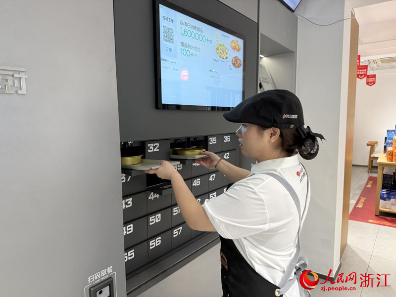 食堂工作人员“AI星厨”智能鲜食机上取餐。人民网记者 方彭依梦摄