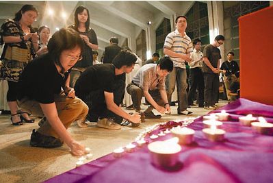 席追思会的校友及市民点起烛光,悼念梁锦荣。